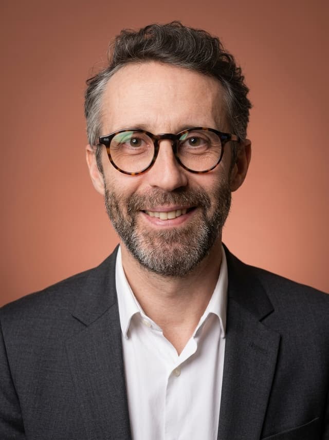 Portrait professionnel style Corporate Chaleureux : fond terracotta, sourire naturel, blazer sombre